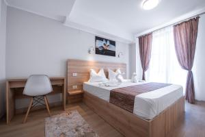a bedroom with a bed and a desk and a chair at Polu-X in Vama Veche
