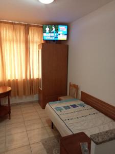 a bedroom with a bed and a tv on the wall at ALOJAMIENTO PLAYA CHICA, LOS POZOS HABITACIONES in Puerto del Rosario