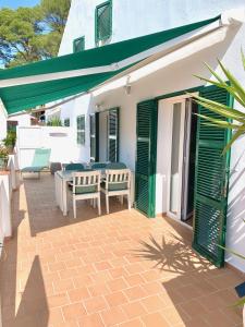 a patio with a table and chairs and green shutters at Es Cucó in Cala Galdana