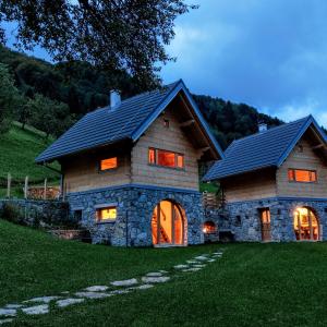 a house with a gambrel roof on a green field at Granaries Pear & Walnut in Tolmin
