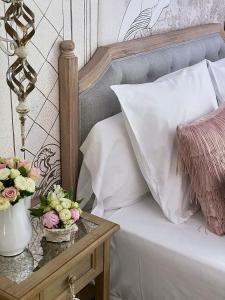 Hotel Boutique Txanka Erreka PARKING INCLUIDO في أوريو: سرير مع وسادة بيضاء وزهور على طاولة