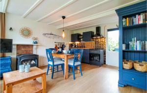 a kitchen with blue cabinets and a table and chairs at Stunning Home In Scherpenisse With Wifi in Sint Maartensdijk