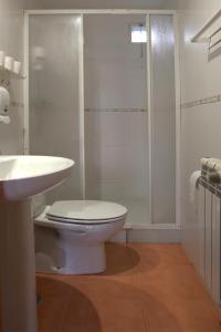 a white bathroom with a toilet and a shower at Apartamentos El Campal in Felechosa