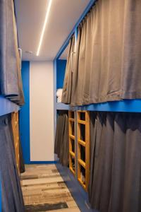 Cette chambre dispose de murs et de rideaux bleus ainsi que d'une fenêtre. dans l'établissement Albergue playa de sabaris, à Sabaris