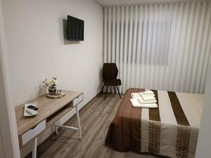 um quarto com uma cama, uma escrivaninha e uma televisão em Olhares do Lobo em Ponte da Barca