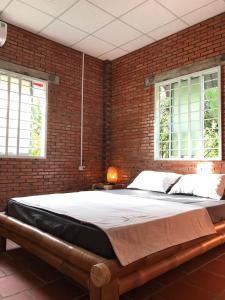 ein Schlafzimmer mit einem großen Bett in einer Ziegelwand in der Unterkunft Nguyet Que Homestay & Tours in Ben Tre