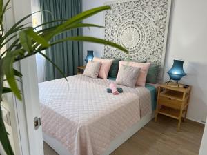 een slaapkamer met een bed met roze kussens en een plant bij TENERO APARTAMENTO TENERIFE EL DORADO in Playa de las Americas