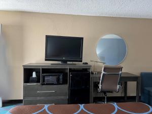 Habitación con TV, silla y espejo. en Super 8 by Wyndham Newport News en Newport News