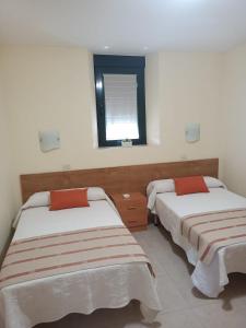 Duas camas num quarto com uma janela em APARTAMENTOS OUTEIRO em Póvoa do Caraminhal