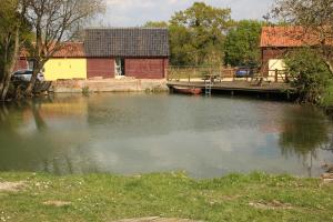 una masa de agua con una casa y un muelle en The Tawny Shepherd Hut, Whitehouse Farm, en Stowmarket
