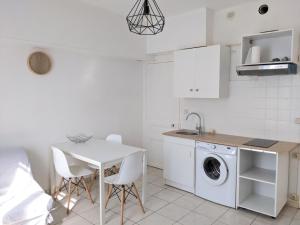 een witte keuken met een tafel en een wasmachine bij Fouras - T2 Hyper centre les pieds dans le sable ! in Fouras