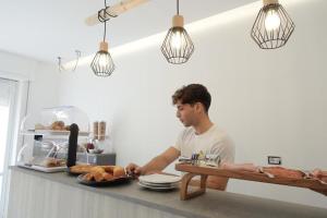 a man standing in a kitchen with a table with bread at KALÓ ROOMS in Tropea