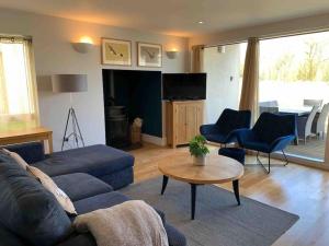 ein Wohnzimmer mit einem blauen Sofa und einem Tisch in der Unterkunft Hoopoe Cottage, Lower Mill Estate in Somerford Keynes