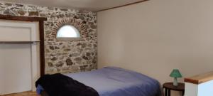 een slaapkamer met een bed met een stenen muur bij Gîtes du Castellare in Le Chalard