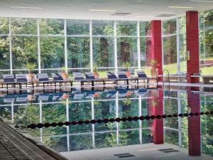 una grande piscina con sedie, tavoli e finestre di CAREA Residenz Hotel Harzhöhe a Hahnenklee-Bockswiese
