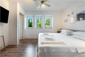 ein weißes Schlafzimmer mit einem großen Bett und Fenstern in der Unterkunft Apartment Near Old Town, FREE PARKING & Huge Garden in Dubrovnik