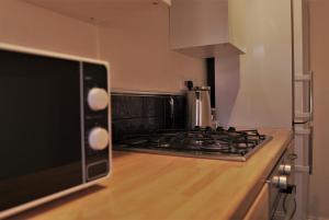 een keuken met een fornuis oven naast een magnetron bij Meadow Terrace in Shrewsbury