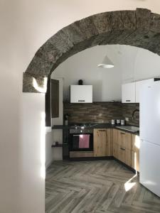 a kitchen with a stone archway and a white refrigerator at L’alcova del centro in Pantelleria