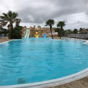 une grande piscine bleue avec un toboggan dans l'établissement Camping 4 etoiles Cap Soleil Oleron, à La Bétaudière