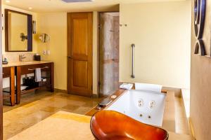 La salle de bains est pourvue d'une baignoire avec une chaise. dans l'établissement Grand Fiesta Americana Los Cabos All Inclusive Golf & Spa, à Cabo San Lucas