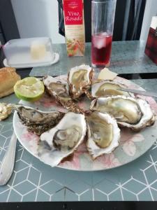 une assiette d'huîtres sur une table avec une boisson dans l'établissement Location saisonniere, à Cozes