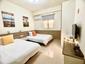 Jinningにある八八古藝悅禾民宿のベッド2台とテレビが備わるホテルルームです。