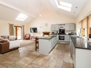 a kitchen with white cabinets and a living room at 2 Pheasant Lane in Deepcar