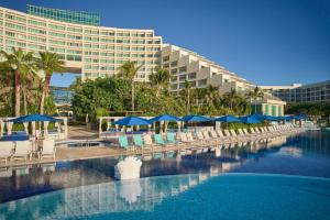 ein Schwimmbad mit Liegestühlen und Sonnenschirmen und ein Hotel in der Unterkunft Live Aqua Cancun - Adults Only - All-Inclusive in Cancún