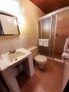 a bathroom with a white toilet and a sink at Hotel y Restaurante Villa Esmeralda in Quetzaltenango