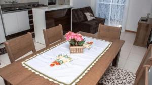 una mesa de comedor con un jarrón de flores. en Lindo Apartamento, amplo e confortável, Penha Santa Catarina,, en Penha