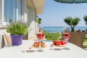 two glasses of wine on a table with the ocean in the background at Hermes Beach Front in Stalos