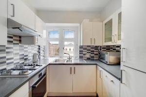 a kitchen with white cabinets and a sink at The Prince's Apartment in London