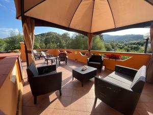 a balcony with chairs and tables and an umbrella at B&B Da Sabrina in San Teodoro