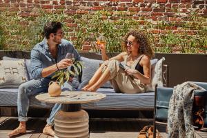 un homme et une femme assis sur un canapé en train de boire du vin dans l'établissement The Pinch Charleston, à Charleston