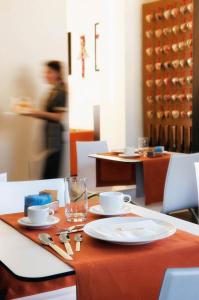 un tavolo con una tovaglia arancione, piatti e bicchieri di Hotel Cimarosa a Napoli