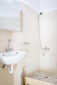 a white bathroom with a sink and a shower at Myrtia Vacation Home in Karpathos Town