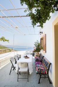 un patio con mesa, sillas y el océano en Myrtia Vacation Home, en Karpathos