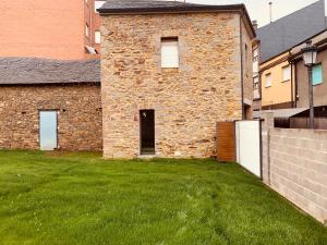 um edifício de tijolos com um quintal com relva verde em Casa de la Abuela em Fabero