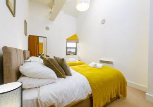 a bedroom with a bed with a yellow blanket on it at K Suites - Barton Court in Warrington