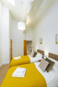 two beds in a room with yellow and white at K Suites - Barton Court in Warrington