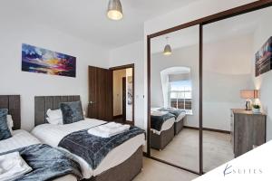 a bedroom with two beds and a mirror at K Suites - Denmark House in Welwyn Garden City