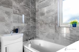 baño con bañera blanca y ventana en K Suites - Bristol Filton en Bristol