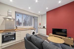 een keuken en een woonkamer met een bank en een televisie bij K Suites - Waveney Chambers 1 in Lowestoft