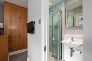 een badkamer met een glazen douche en een wastafel bij 5 Doughty Street - Urban Apartments in Londen +43 foto's