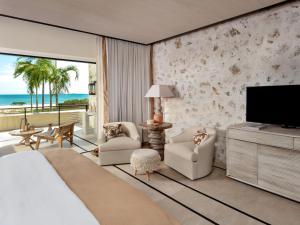 a bedroom with a bed and a tv and a balcony at Susurros del Corazón, Auberge Resorts Collection in Cruz de Huanacaxtle