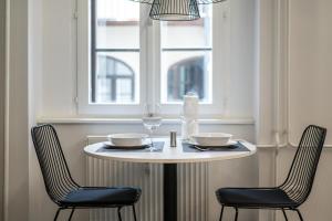 a white table with two chairs and a window at Strict city apartments in Ljubljana