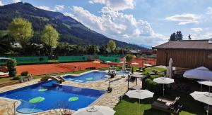 a pool with a tennis court and a tennis court at Vital & Sporthotel Brixen in Brixen im Thale