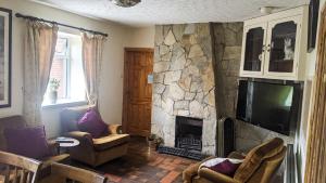 a living room with a stone fireplace and a television at Lough Shore Cottage in Magherafelt