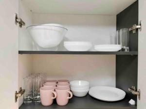 a shelf with bowls and plates and other dishes in a kitchen at Lovely 3-bedroom apartment in the city center in Timişoara
