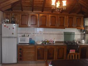 cocina con armarios de madera y nevera blanca en Adega do Batista en Calheta